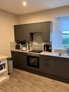 uma cozinha com um lavatório e um fogão forno superior em Newly refurbished flat - Callander em Callander