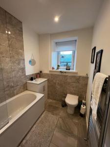 y baño con bañera, aseo y lavamanos. en Newly refurbished flat - Callander en Callander