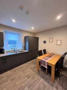 een keuken met een houten tafel en een tafel en stoelen bij Newly refurbished flat - Callander in Callander