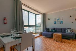 uma sala de estar com uma mesa e um sofá azul em Grand Harbour View em Birgu