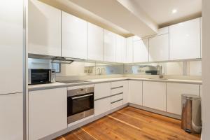 a white kitchen with wooden floors and white cabinets at Beautiful 2-Bed Apartment in London in London