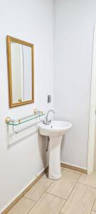 een badkamer met een witte wastafel en een spiegel bij Kapowlito Real Estate Casa #3+4 Mon Plaisirweg in Paramaribo