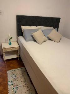 a large white bed with two pillows and a table at Casa bem localizada e espaçosa no Butantã in São Paulo