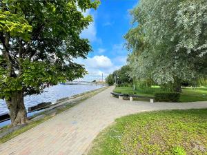 a brick walkway next to a river with benches at Ziemeļblāzma in Rīga