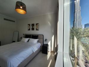 a bedroom with a bed and a large window at Downtown Oasis, Burj Khalifa Views, Luxury Amenities in Dubai
