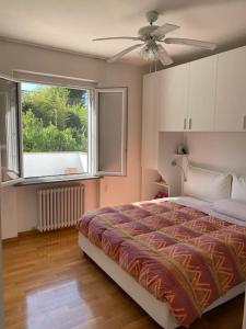 a bedroom with a bed with a ceiling fan and a window at Villetta familiare a Potenza Picena in Potenza Picena