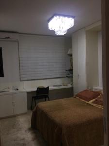 ein Schlafzimmer mit einem großen Bett und einem Kronleuchter in der Unterkunft Condomínio Edificio Ilhabela Residence in Uberlândia