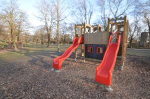 a playground with two red slides in a park at Sweet apartment in Bratislava