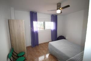 een slaapkamer met een bed en een raam met paarse gordijnen bij Apartamento Maria Paz Cambrils in Cambrils