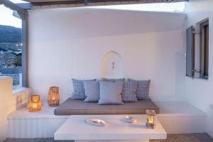 Un banco en un balcón con una mesa y luces. en Sirma Beach House, en Kimolos