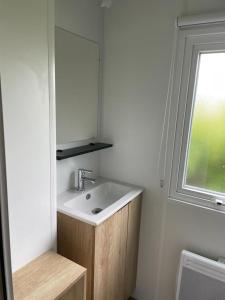 ein Badezimmer mit Waschbecken, Spiegel und Fenster in der Unterkunft Mobilhome-vue lac-4 étoiles -Lac des Rêves in Lattes
