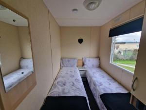 Habitación pequeña con 2 camas y ventana en Lunaeva Holiday Home, en Saint Osyth