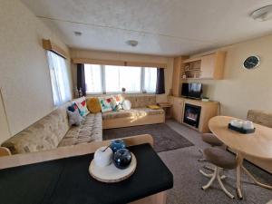a living room with a couch and a table at Lunaeva Holiday Home in Saint Osyth