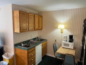 a kitchen with a sink and a table with a microwave at Stowe Motel & Snowdrift in Stowe