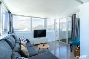 a living room with a couch and a flat screen tv at Apartamentos Sea Breeze in Famara