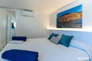a bedroom with a large white bed with blue pillows at Apartamentos Sea Breeze in Famara
