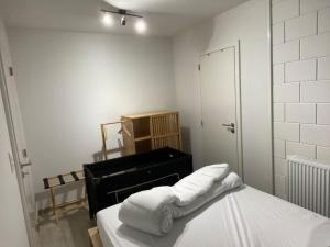 um quarto branco com um piano e toalhas numa cama em Le P'tit Padré em Jalhay