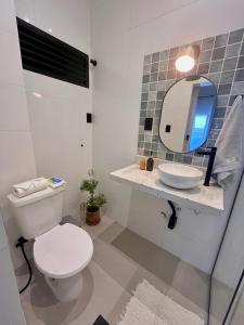 W łazience znajduje się biała toaleta i lustro. w obiekcie Apartamento Glória w mieście Rio de Janeiro