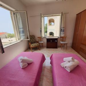 two beds in a room with pink sheets and windows at Casa ponente...a due passi dal mare in Porto Alabe