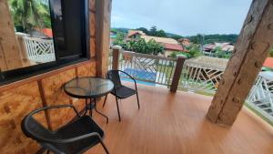 uma varanda com 2 cadeiras, uma mesa e uma janela em LS Resthouse with pool and garden em Calapan