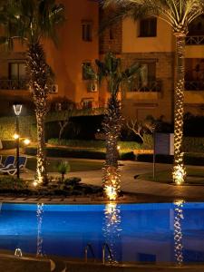 a pool with palm trees and lights next to a building at Luxury Chalet in Mountain View 2 , El-Sokhna with Sea View , Pool View "Heated Pool" and Garden View Families Only in Ain Sokhna