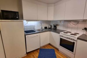 a kitchen with white cabinets and a stove and a sink at Leilighet på Bekkeli, Beito. in Beitostøl