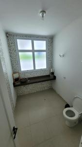 a bathroom with a toilet and a window at Casa Praia dos Sonhos in Itanhaém