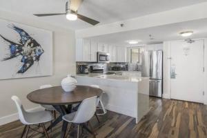 a kitchen with a table and chairs and a kitchen with a refrigerator at The Scallop by Brightwild-Beachfront Condo in Destin