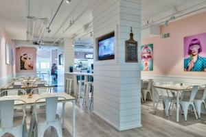 a dining room with tables and chairs and paintings on the walls at The Scallop by Brightwild-Beachfront Condo in Destin