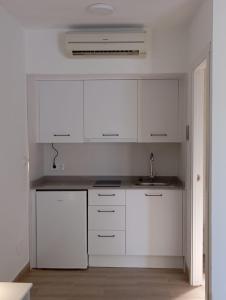 una cocina blanca con armarios blancos y fregadero en El Levante en Tarifa