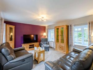 een woonkamer met 2 leren banken en een tv bij 3 Bed in Corfe Castle 81369 in Corfe Castle