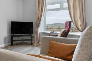 a living room with a couch and a large window at Sperrin Mountain Escape in Derry Londonderry