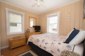 a bedroom with a bed and a tv and two windows at The Montauk Soundview in Montauk