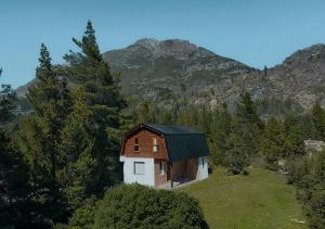 una pequeña casa en una colina con montañas en el fondo en Los Cauces - Reserva Cannábica en Epuyén