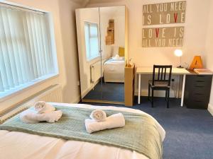 4 bed House Royal Leamington Spa with free parking في ليمينغتون سبا: غرفة نوم مع منشفتين على سرير مع مرآة