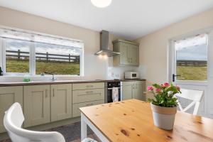a kitchen with a wooden table and a kitchen with windows at Sperrin Mountain Escape in Derry Londonderry