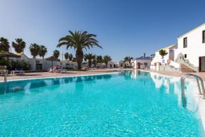 een zwembad met blauw water in een resort bij Bungalow Montecastillo i1 in Caleta De Fuste