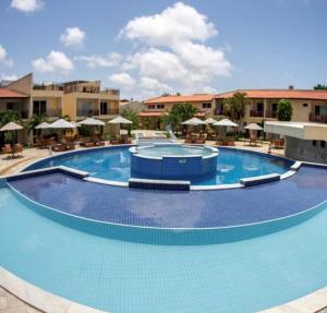 una gran piscina con sillas y sombrillas en Flat todo ambientado no coração de Pipa - Solar Água Apart Hotel, en Pipa