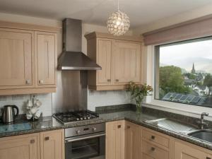 cocina con armarios de madera, fregadero y ventana en 2 Bed in Keswick SZ008, en Keswick