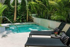 a swimming pool with a bench and a chair next to it at Carriage House at Grand Maloney by Brightwild in Key West