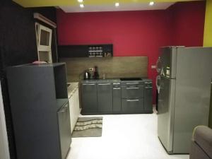 a kitchen with a stainless steel refrigerator and red walls at Rawdat Zayed Compound in Sheikh Zayed