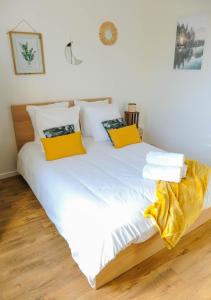 Bett mit weißer Bettwäsche und gelben Kissen in der Unterkunft Cosy Casa entre Paris et Disney in Neuilly-Plaisance