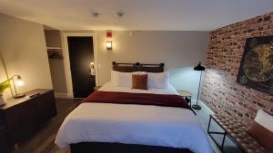 1 dormitorio con 1 cama grande y pared de ladrillo en Gunstock Inn & Suites, en Gilford