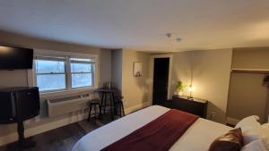 1 dormitorio con 1 cama, TV y ventana en Gunstock Inn & Suites en Gilford