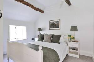 a white bedroom with a white bed and a window at Two Rose Walk Cottage Cotswolds in Moreton in Marsh +34 photos