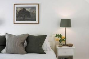 ein Schlafzimmer mit einem Bett mit einem Bild an der Wand in der Unterkunft Two Rose Walk Cottage Cotswolds in Moreton-in-Marsh