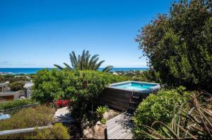 a swimming pool in a garden with the ocean in the background at The Sea Soul in Cape Town