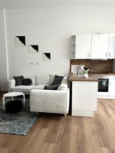 ファーレルにあるSuite One Langestraßeのリビングルーム(白いソファ付)、キッチンが備わります。