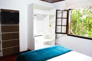 um quarto com uma cama, uma janela e uma televisão em Pousada Casa de Campos Guest em Campos do Jordão