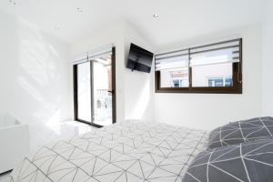 a white bedroom with a bed and two windows at Aqua Viva - Playa San Juan in Playa de San Juan